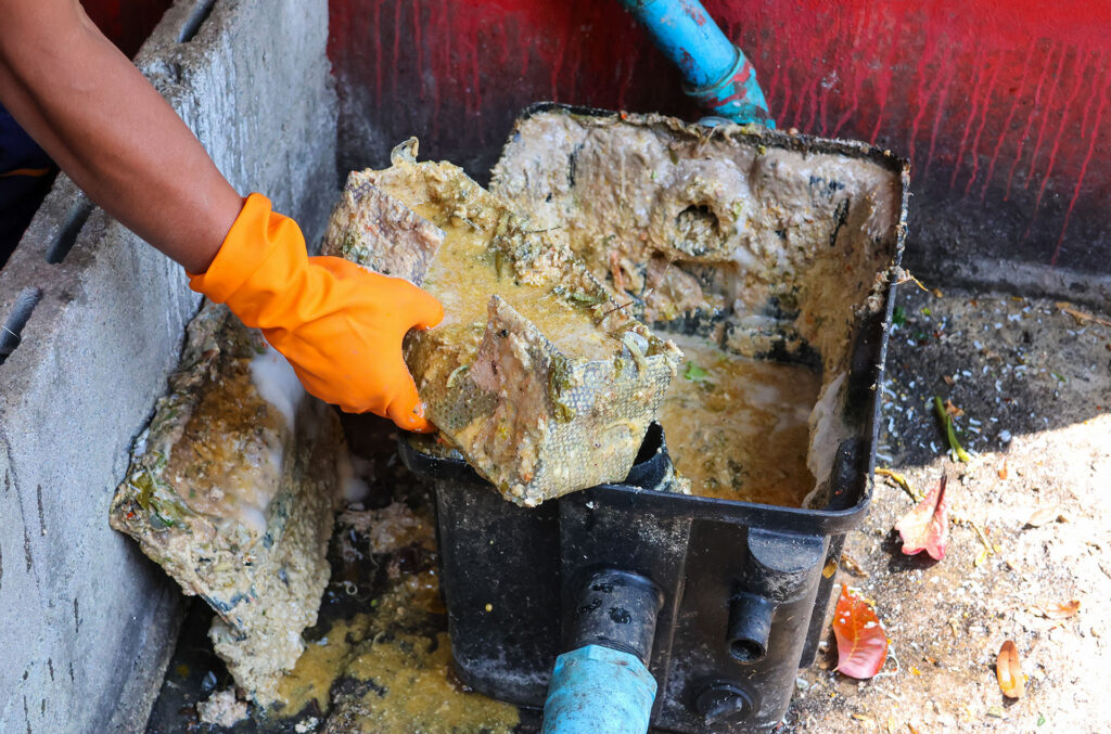 dirty grease trap being cleaned